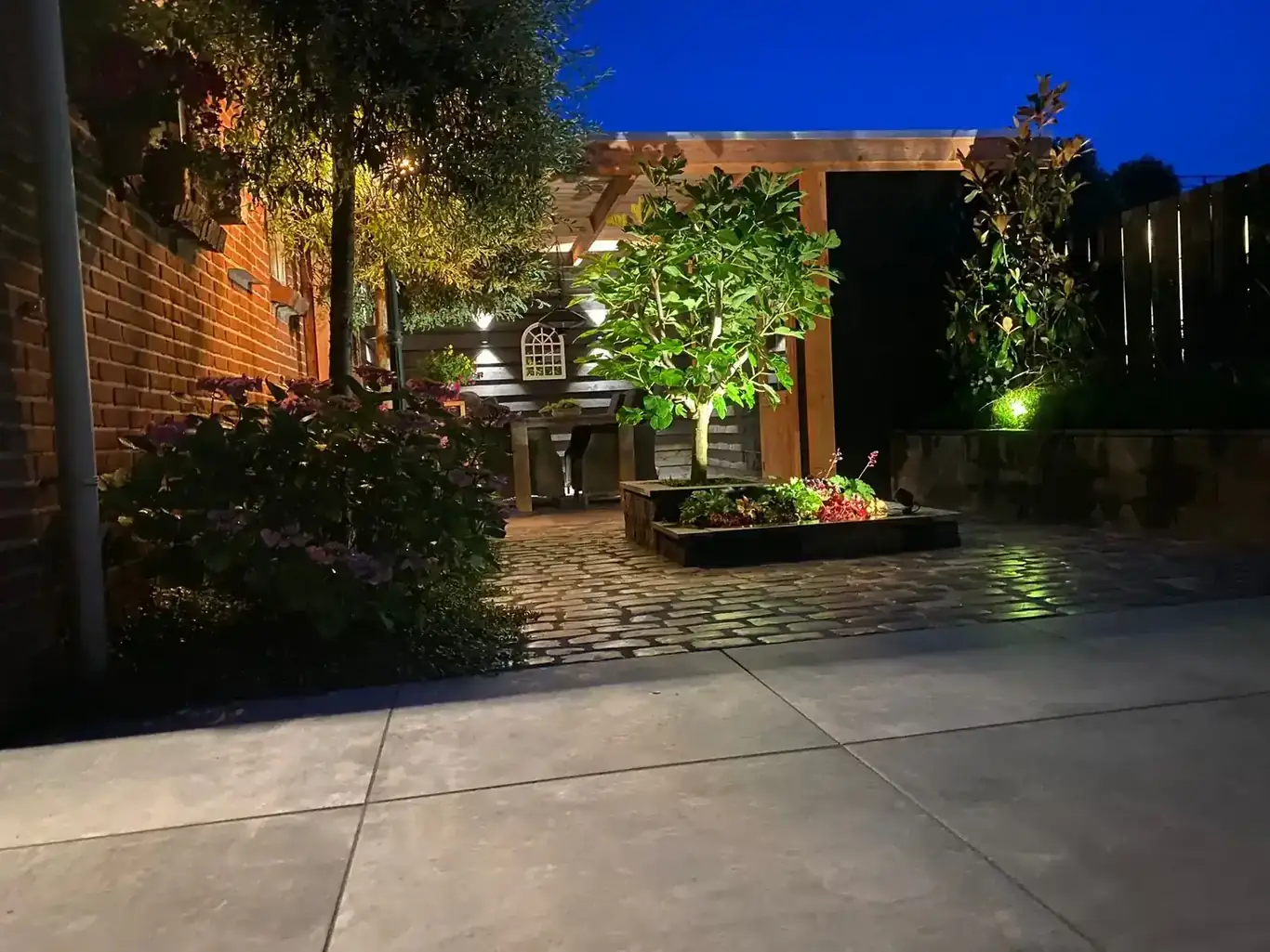 Sfeervol verlichte tuin met tuinverlichting in de avond, aangelegd door hovenier GS Gardens in Nieuw-Vennep