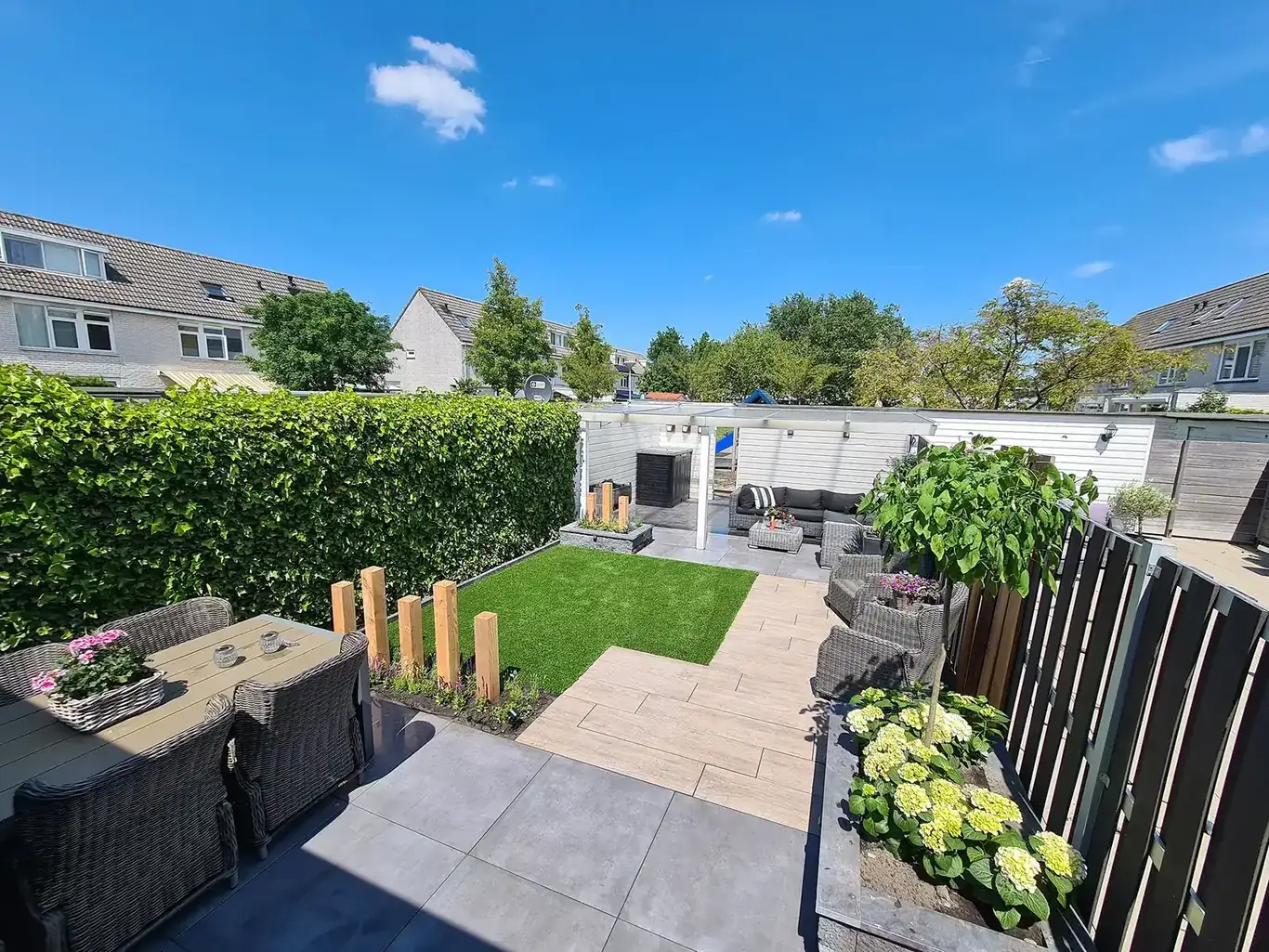 Zonnige achtertuin met bestrating, gazon en beplanting — tuinaanleg door GS Gardens in Nieuw-Vennep