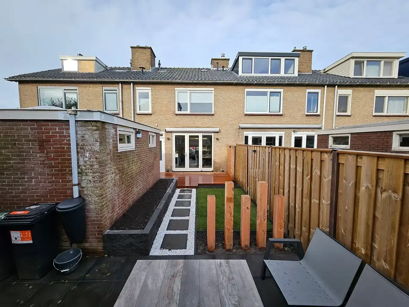 Nieuw aangelegde achtertuin met vlonder en stapstenen — tuinaanleg in Nieuw-Vennep